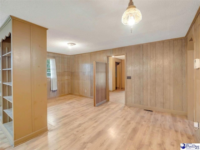 1709 N Irby St, Florence, SC 29501 - unfurnished room featuring a textured ceiling, light wood-style floors, baseboards, and wooden walls