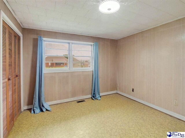 1709 N Irby St, Florence, SC 29501 - unfurnished bedroom featuring wood walls, a closet, and baseboards