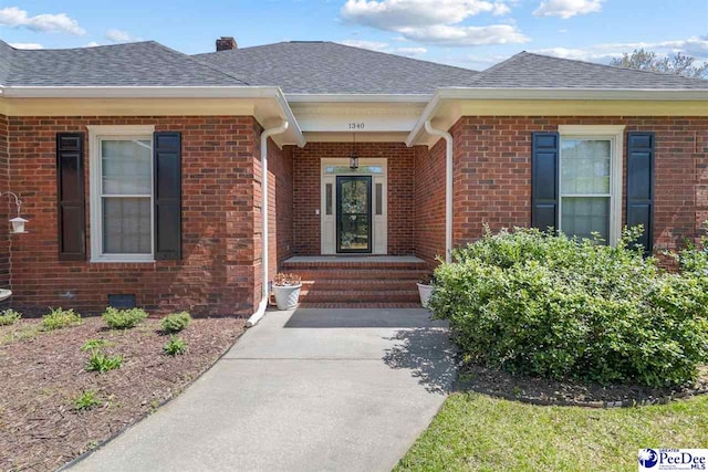 entrance to property with brick siding and roof with shingles