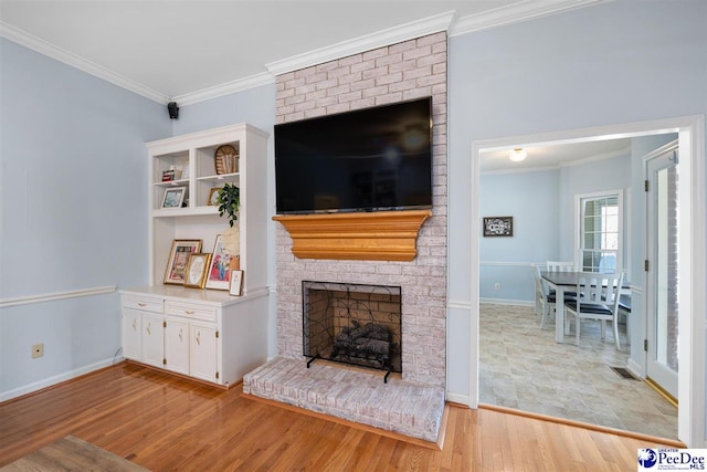 living room with a brick fireplace, crown molding, light wood-style floors, and baseboards