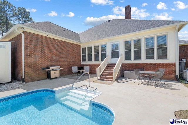 outdoor pool featuring grilling area, entry steps, and a patio area