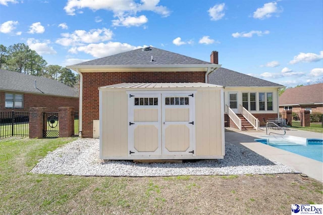 view of shed with a sunroom, fence, and a fenced in pool