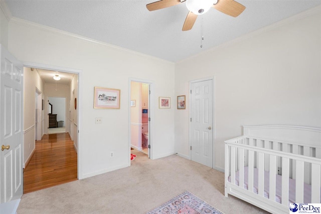 carpeted bedroom featuring crown molding, attic access, baseboards, a textured ceiling, and ceiling fan