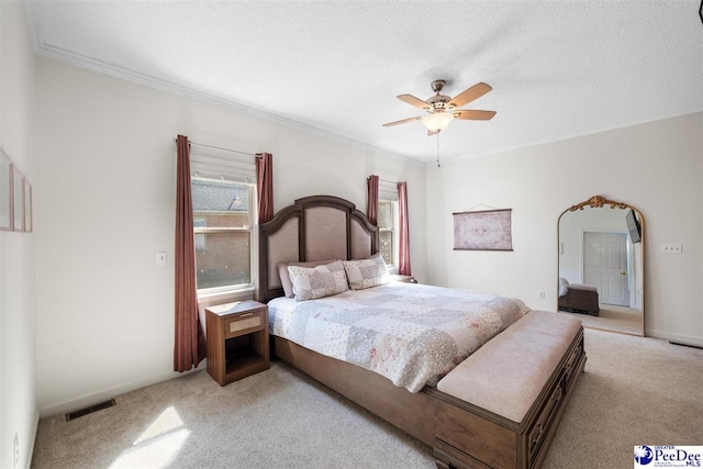 carpeted bedroom featuring a textured ceiling, visible vents, crown molding, baseboards, and a ceiling fan