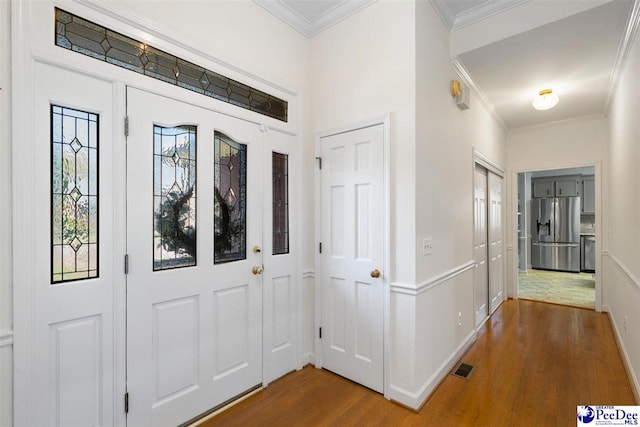 foyer featuring baseboards, ornamental molding, visible vents, and wood finished floors