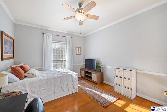 bedroom featuring baseboards, a ceiling fan, wood finished floors, and crown molding