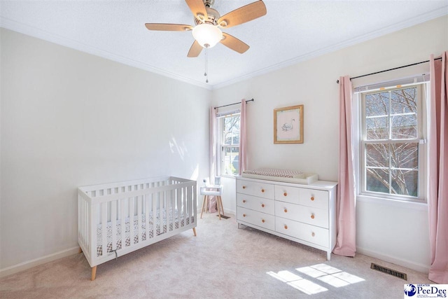 bedroom with carpet floors, ornamental molding, visible vents, and a nursery area