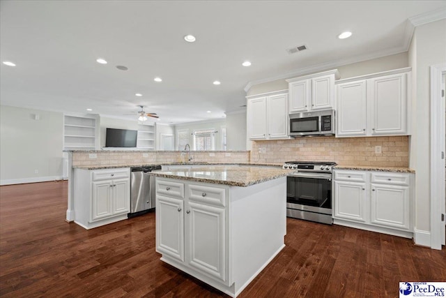 kitchen with white cabinetry, stainless steel appliances, dark hardwood / wood-style floors, a center island, and kitchen peninsula