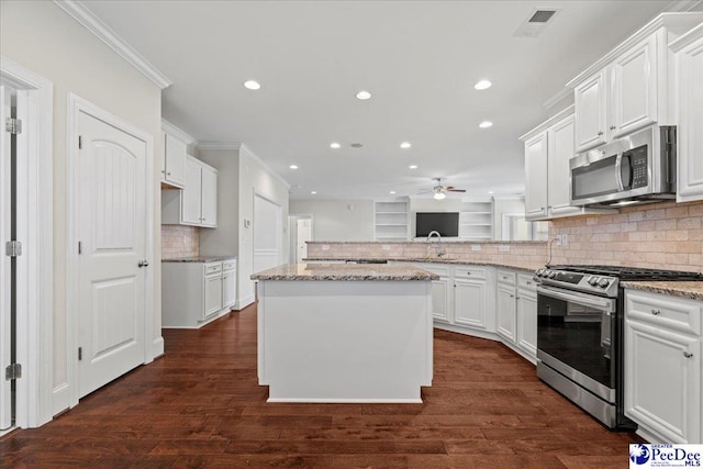 kitchen featuring white cabinetry, a center island, light stone counters, stainless steel appliances, and dark wood-type flooring