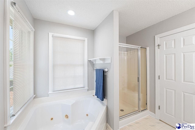 full bathroom featuring a shower stall, a jetted tub, and a textured ceiling