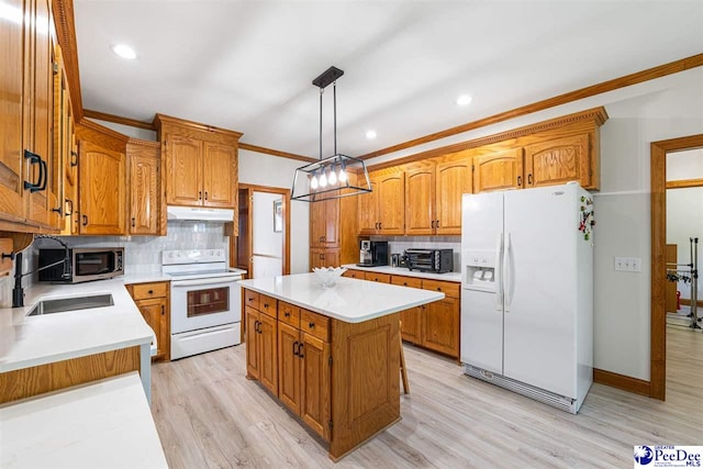kitchen with white appliances, light wood-style flooring, backsplash, a kitchen island, and under cabinet range hood