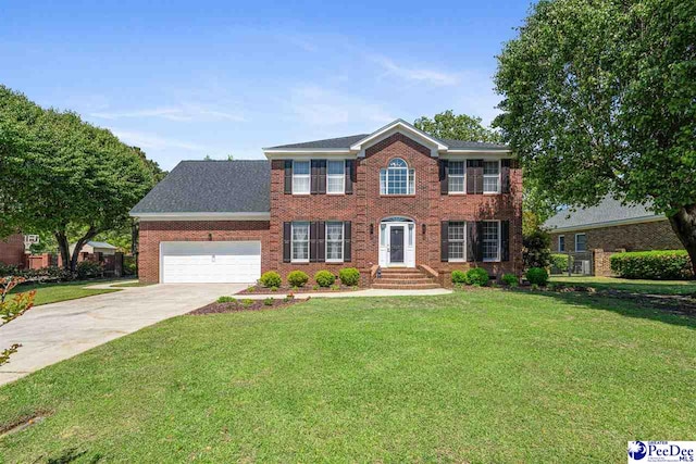 colonial inspired home featuring concrete driveway, a front yard, brick siding, and an attached garage