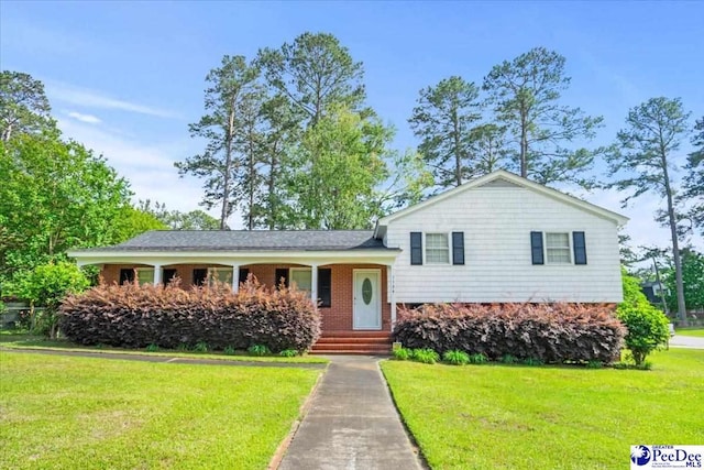 tri-level home featuring a porch, a front lawn, and brick siding