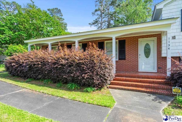 property entrance with brick siding and covered porch