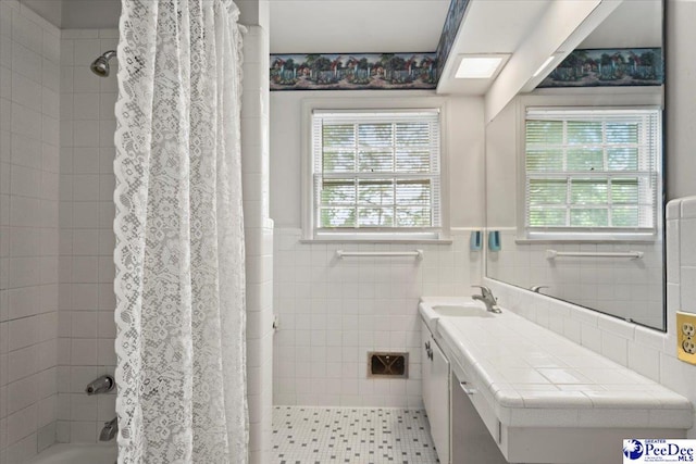 full bath with a healthy amount of sunlight, vanity, and wainscoting