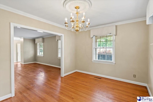 empty room featuring light wood-type flooring, ornamental molding, a notable chandelier, and a wealth of natural light