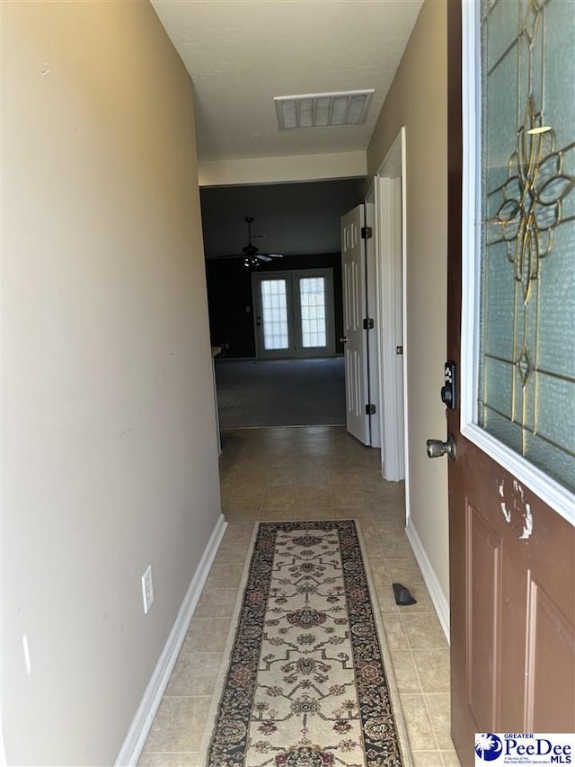 hall featuring light tile patterned floors, baseboards, and visible vents