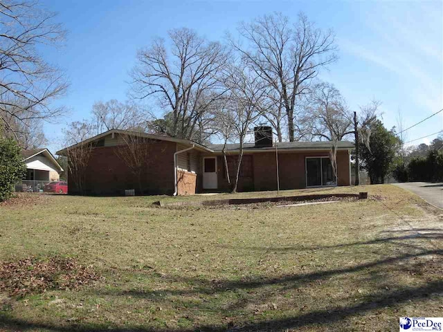 view of front of home with brick siding, a chimney, and a front lawn