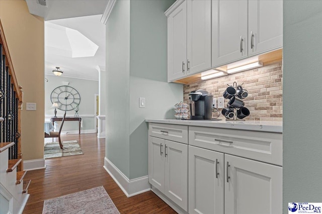 bar featuring white cabinetry, dark hardwood / wood-style flooring, crown molding, and backsplash