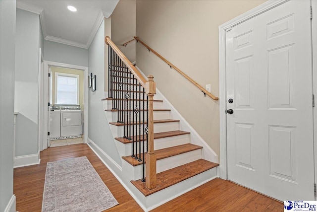 stairway featuring washer and clothes dryer, ornamental molding, and wood-type flooring