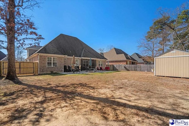 rear view of house featuring a storage unit, a patio area, and a lawn