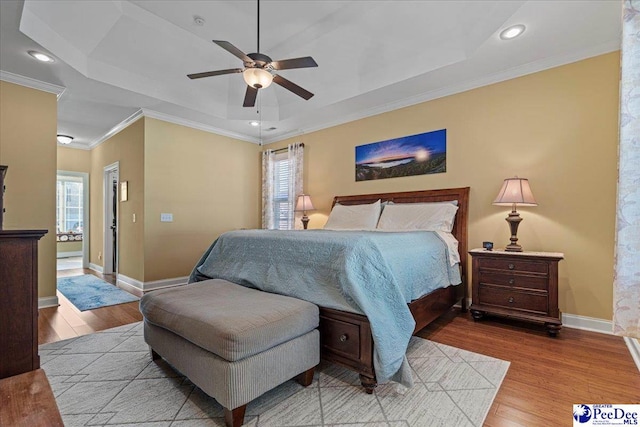 bedroom with a raised ceiling, hardwood / wood-style floors, and multiple windows