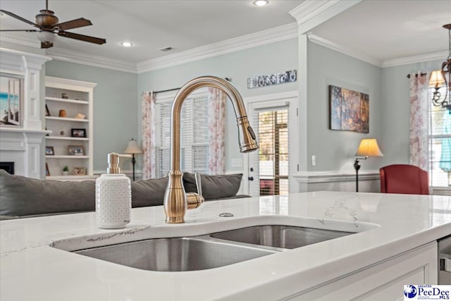 kitchen with ornamental molding, decorative light fixtures, sink, and plenty of natural light