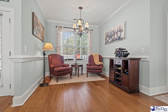 living area featuring hardwood / wood-style flooring, crown molding, and an inviting chandelier