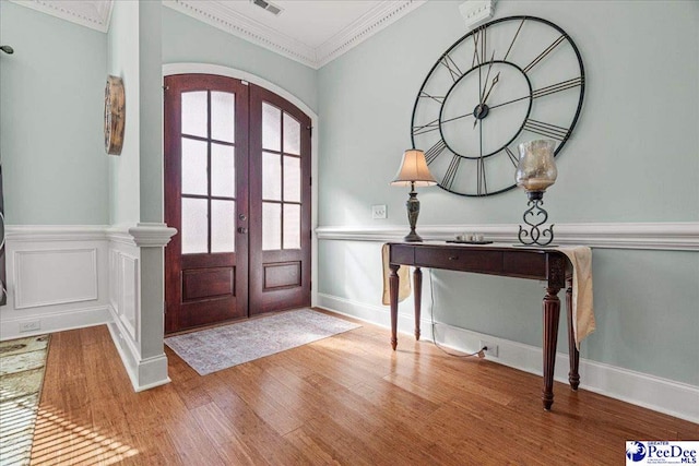 foyer entrance with light hardwood / wood-style flooring, ornamental molding, and french doors