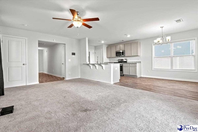 unfurnished living room with dark carpet and ceiling fan with notable chandelier