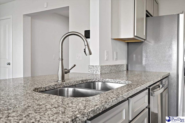 kitchen featuring light stone counters and sink