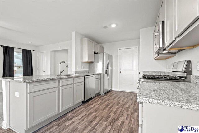 kitchen featuring sink, appliances with stainless steel finishes, gray cabinetry, light stone counters, and dark hardwood / wood-style flooring