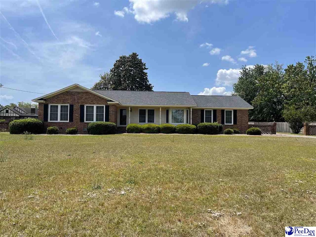 single story home featuring fence, a front lawn, and brick siding