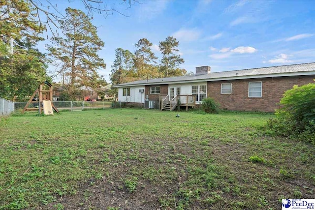 rear view of property featuring a yard, a playground, and a deck