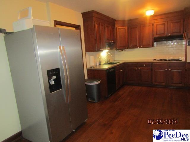 kitchen featuring dark wood-type flooring, sink, decorative backsplash, and black appliances