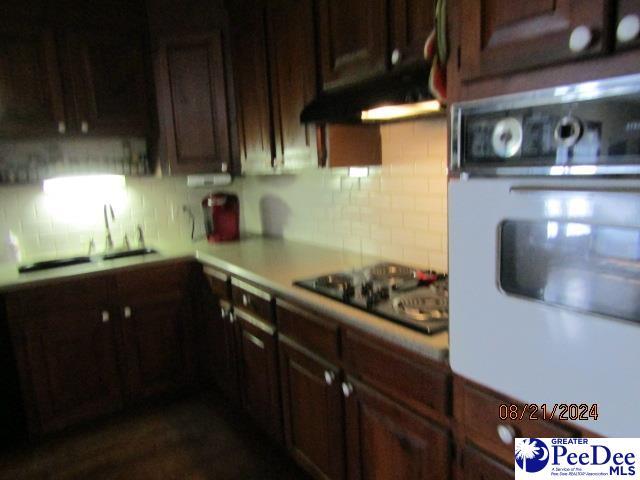 kitchen featuring sink, black electric stovetop, backsplash, and oven