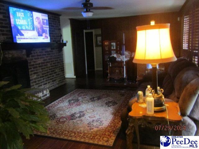 living room with wood-type flooring, a brick fireplace, and ceiling fan