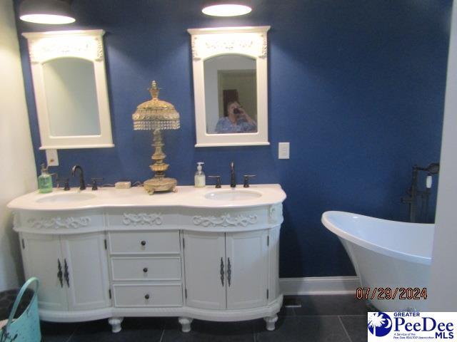 bathroom with tile patterned flooring, vanity, and a washtub