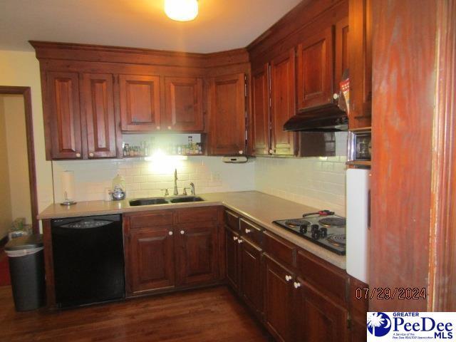 kitchen with tasteful backsplash, sink, dark wood-type flooring, and black appliances