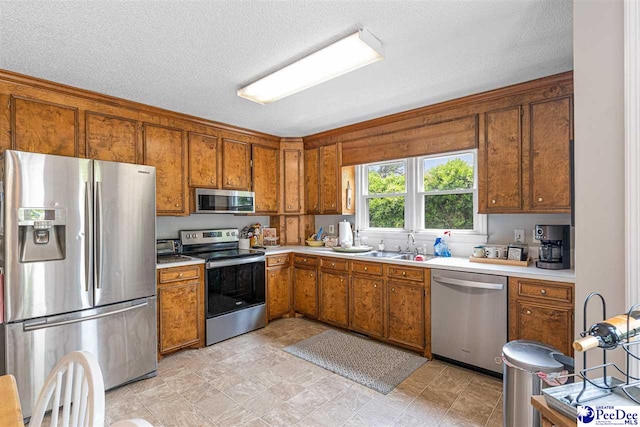kitchen with light countertops, a sink, brown cabinets, and stainless steel appliances