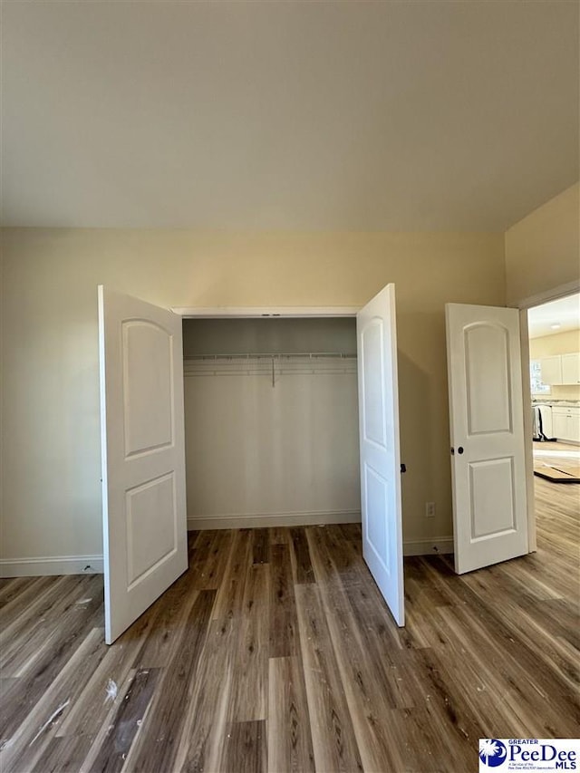 unfurnished bedroom featuring dark hardwood / wood-style flooring and a closet