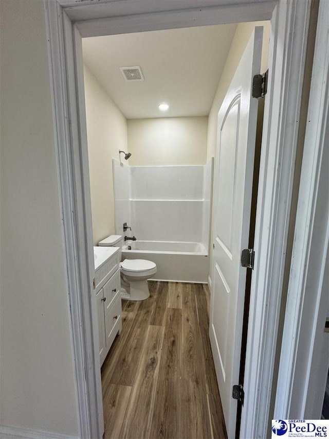 full bathroom featuring vanity, hardwood / wood-style flooring, tub / shower combination, and toilet