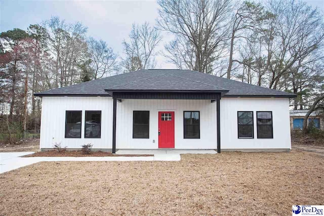 view of front of home with roof with shingles and a front lawn