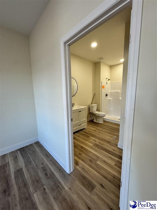 bathroom featuring hardwood / wood-style flooring, a shower, vanity, and toilet