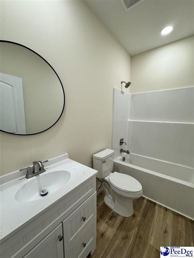 full bathroom featuring hardwood / wood-style flooring, shower / tub combination, vanity, and toilet