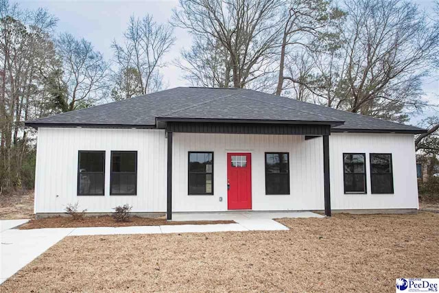 modern farmhouse style home with a shingled roof and a front yard