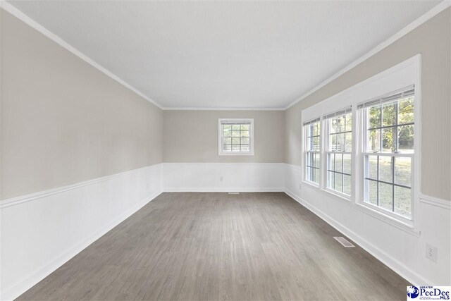 616 Sandra Ter, Florence, SC 29501 - empty room featuring dark wood finished floors, visible vents, ornamental molding, and a wainscoted wall
