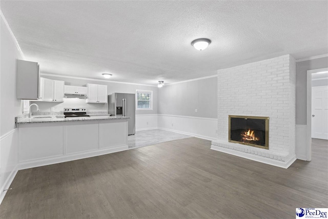 616 Sandra Ter, Florence, SC 29501 - unfurnished living room with a brick fireplace, a sink, a textured ceiling, and wood finished floors