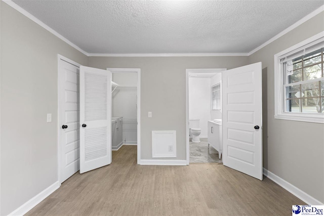 616 Sandra Ter, Florence, SC 29501 - unfurnished bedroom featuring a closet, a walk in closet, crown molding, and light wood-style floors