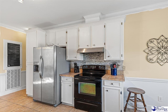 kitchen with white cabinetry, black / electric stove, ornamental molding, stainless steel fridge, and tile counters